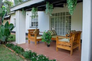 LobambaRehoboth Ezulwini Suites的庭院设有长凳和桌椅。