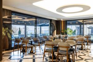 a room with chairs and tables and windows at Ezkar Bathonea Art İstanbul Hotel in Avcılar