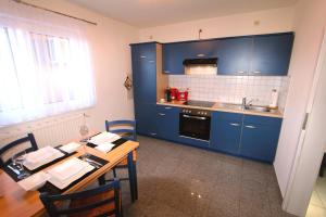 a kitchen with blue cabinets and a table with chairs at FERIENHAUS SEENSUCHT in Malchow