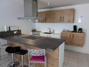 a kitchen with a counter and some chairs in it at Suites privatives in Guer