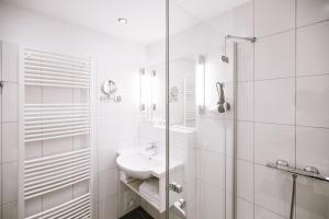 a white bathroom with a sink and a shower at Hotel Stadt Kassel in Rinteln +39 photos