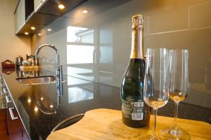 a bottle of wine and two wine glasses on a counter at The Dome Boutique Apartments in Napier +80 photos