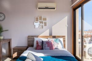 ein Schlafzimmer mit einem Bett mit Kissen und einem Fenster in der Unterkunft Ani's Stylish Studio W Terrace in Larnaca in Larnaka