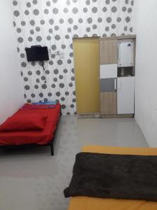 a room with a red bed and a refrigerator at Ahza syariah in Rantauprapat