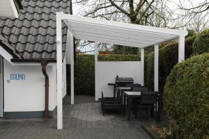 eine weiße Pergola mit Tischen und Stühlen auf einer Terrasse in der Unterkunft Eine sehr gemütliche Erdgeschoß Wohnung in Ihlow