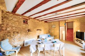 ein Wohnzimmer mit Tisch und Stühlen und einem Fernseher in der Unterkunft Maison en pierre avec piscine et terrasse pour 6 in Montignac