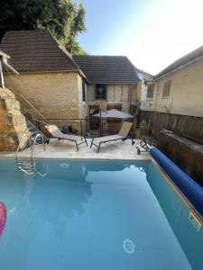 ein Swimmingpool in einem Hinterhof mit einem Tisch und Stühlen in der Unterkunft Maison en pierre avec piscine et terrasse pour 6 in Montignac