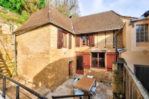 ein altes Backsteinhaus mit einem Tisch auf einer Terrasse in der Unterkunft Maison en pierre avec piscine et terrasse pour 6 in Montignac