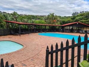 a swimming pool with a pavilion and a fence at 37 Chakas Rock Chalets in Ballito