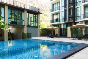 a swimming pool in front of a building with umbrellas at Forest Khaoyai by Licega in Ban Huai Sok Noi