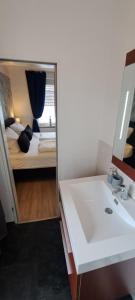 ein Bad mit einem Spiegel, einem Waschbecken und einem Bett in der Unterkunft FeWo-Butze 3 Esens in Esens