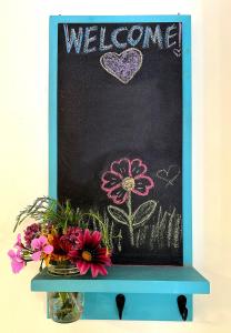 a blackboard with a welcome sign and flowers on it at Couples Cottage l Steps to Downtown in Solvang