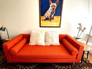 an orange couch in a living room with a picture of a dog at Couples Cottage l Steps to Downtown in Solvang +42 photos