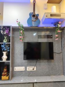 TV de pantalla plana en un centro de entretenimiento con guitarra en Kartikey Home Stay, en Varanasi