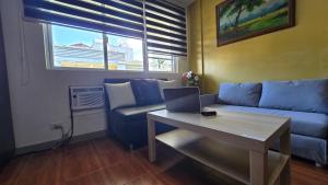 大雅台Staycation Tagaytay Albizia的客厅里有一张沙发和一张带笔记本电脑的桌子