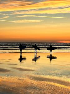 three people walking on the beach with their surfboards at Luxury coastal retreat - On-site parking - sleeps 4 in Ilfracombe