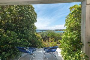 two blue chairs on a patio with a view of the water at Vista Playa 2 in Isola di Porticciuolo