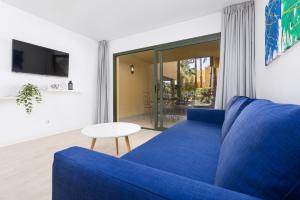 a blue couch in a living room with a table at Home2Book Poolside & Terrace Retreat, Corralejo in La Oliva