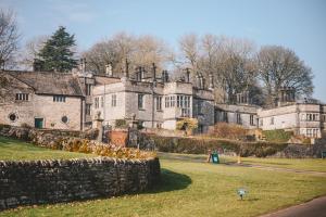 un vieux château avec un mur en pierre devant lui dans l'établissement Nurse's Cottage, Tissington, Derbyshire, à Ashbourne