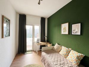 a living room with a couch and a green wall at Big apartment with Parking, 30 min to Düsseldorf in Duisburg