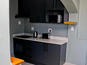 a kitchen with black cabinets and a white counter top at Wokuphumla in East London