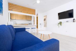 a living room with a blue couch and a table at Home2Book Poolside & Terrace Retreat, Corralejo in La Oliva