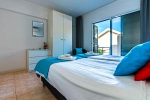 a bedroom with a large bed with blue pillows at Casa Flora, 2 quartos,vista mar in Arco da Calheta