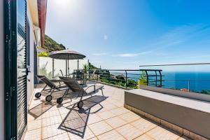 a balcony with two chairs and an umbrella at Casa Flora, 2 quartos,vista mar in Arco da Calheta