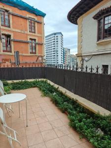 un patio avec une table et une clôture avec des plantes dans l'établissement Vicaria, à Gijón