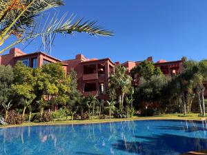 a resort with a swimming pool in front of a building at Accès direct piscine - appartement avec jardin in Marrakesh