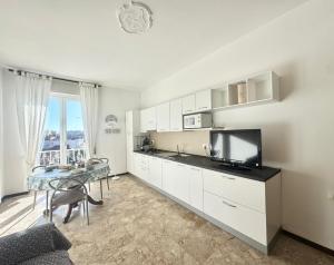 a kitchen with white cabinets and a table with a tv at Casa Dante in Finale Ligure