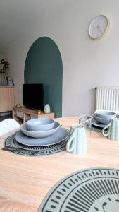 a dining room table with plates and a clock on the wall at L'Escale near Airport Orly and Paris in Athis-Mons