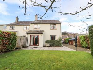 a white house with a patio and yard at Ash Gill Cottage in Coniston