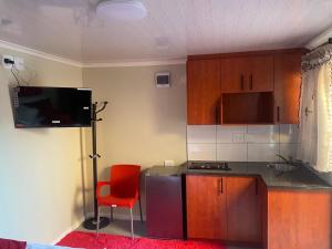 cocina con silla roja, barra y TV en SABATH LODGE, en Ciudad del Cabo