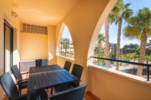 einen Balkon mit einem Tisch, Stühlen und Palmen in der Unterkunft Playa Marina by Ĥ - Playa Punta del Moral PPHM319P74 in Punta del moral