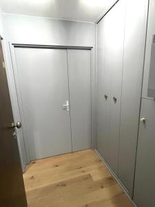 ein leeres Zimmer mit grauen Türen und Holzboden in der Unterkunft Les Glycines in Le Touquet-Paris-Plage