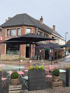 a cafe with tables and umbrellas in front of a building at Vakantiewoning Bij de Jep in Bilzen