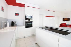 a white kitchen with white cabinets and red accents at Ferienwohnung Leuchtfeuer 6 OG in Peenemünde