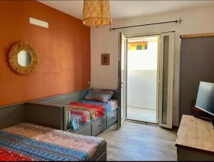 een kamer met twee bedden en een glazen schuifdeur bij Casa Marisol in Orosei