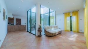 a living room with a white couch and glass walls at Villa Areias II - Beautiful landscape garden in Estói +24 photos