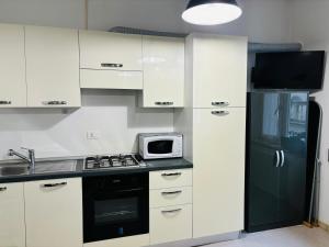 a kitchen with white cabinets and a black refrigerator at In centro dalla Stefy in Udine
