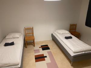 2 camas en una habitación con 2 sillas y una alfombra en Asunto työporukalle Ollintie 1b2, en Uimaharju 5 fotos más