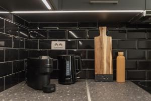 - une cuisine avec des murs carrelés noirs, une cafetière et un couteau dans l'établissement Saint Matthew Central Apartment by Senaon, à Héraklion
