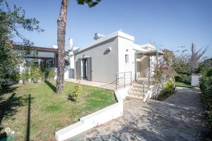 a white house with a tree and a yard at 'Red Port'Amazing House 5 min from the sea in Rafina