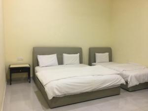 two beds with white sheets in a room at Bonsai Homestay Kluang - Meranti in Kluang +25 photos