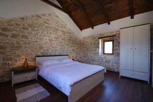 een slaapkamer met een bed en een stenen muur bij Villa Dora with private pool in Gradina