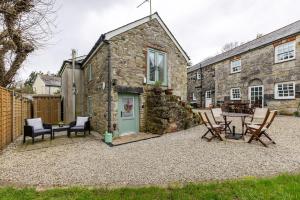 a stone house with a table and chairs in front of it at Blaise Cottage Cornwall in St Austell