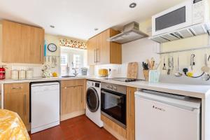 a kitchen with white appliances and wooden cabinets at Blaise Cottage Cornwall in St Austell