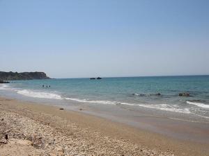 a beach with people swimming in the ocean at Skidi Beach house in Ágios Matthaíos