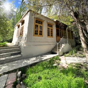 a small white house with yellow windows and stairs at Grapes Garden Resort Hunza in Hunza Valley